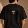 THE HOUSE TEE — INK — editorial back (model) Editorial lookbook mockup: black THE HOUSE TEE — INK worn by a model, back view with the small gold-coloured Luxoriq phoenix crest