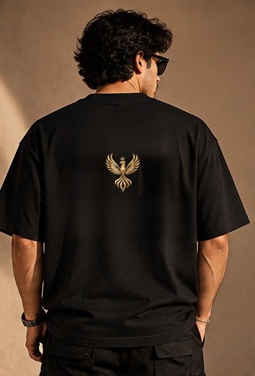 THE HOUSE TEE — INK — editorial back (model) Editorial lookbook mockup: black THE HOUSE TEE — INK worn by a model, back view with the small gold-coloured Luxoriq phoenix crest