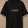 THE HOUSE TEE — INK — editorial front (flat) Editorial lookbook mockup: black THE HOUSE TEE — INK laid flat, front view with the small ivory LUXORIQ wordmark and IN EVERY THREAD