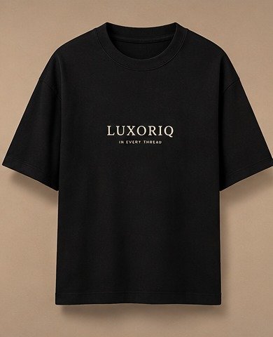 THE HOUSE TEE — INK — editorial front (flat) Editorial lookbook mockup: black THE HOUSE TEE — INK laid flat, front view with the small ivory LUXORIQ wordmark and IN EVERY THREAD